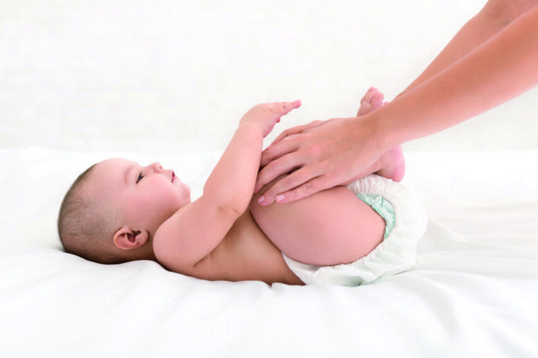 mother massaging her newborn baby in bed
